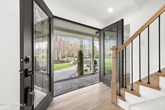 foyer entrance featuring crown molding, stairway, and wood finished floors