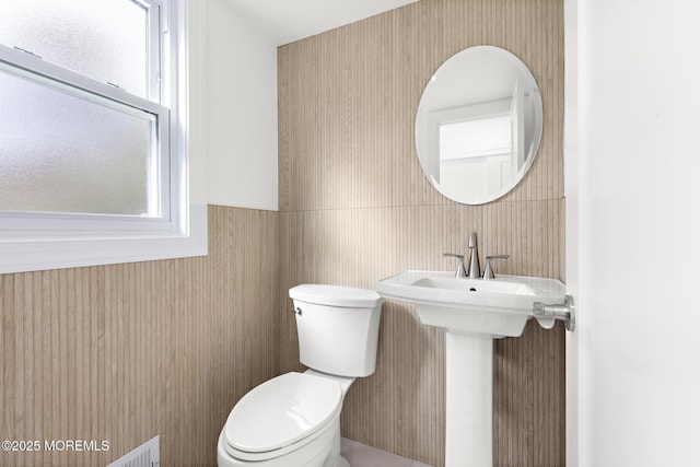 bathroom featuring toilet and a wainscoted wall