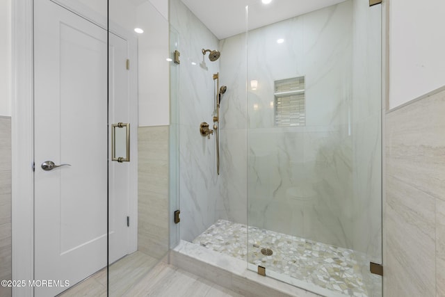 bathroom with tile walls and a marble finish shower