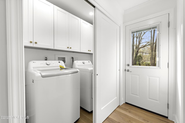 washroom featuring light wood-style floors, ornamental molding, cabinet space, and washing machine and clothes dryer