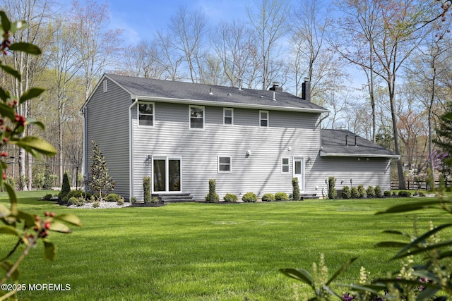 back of property featuring a lawn, a chimney, and a shingled roof