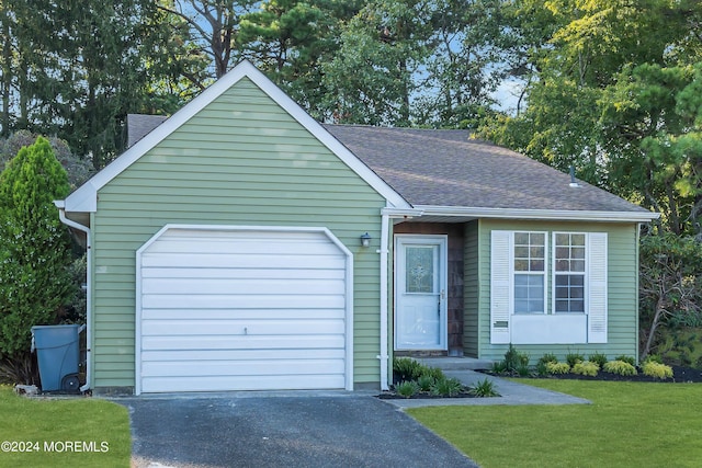 ranch-style house with roof with shingles, a front lawn, driveway, and an attached garage