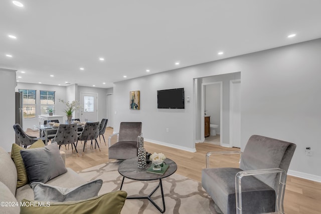 living room featuring baseboards, recessed lighting, and light wood-style flooring