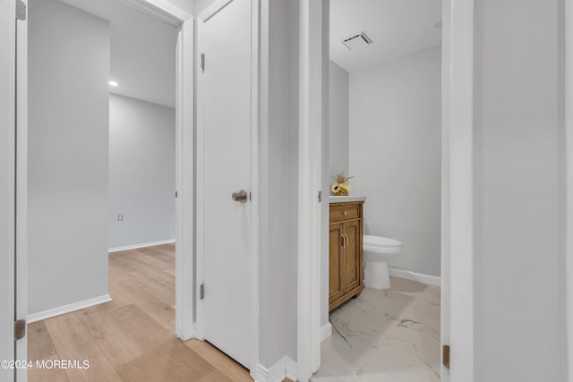 hallway with marble finish floor, visible vents, and baseboards