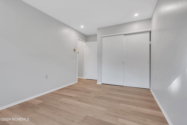 unfurnished bedroom with baseboards, recessed lighting, light wood-style floors, and a closet