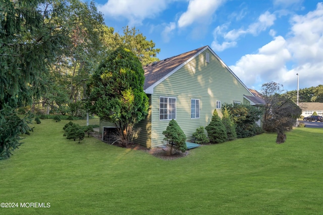 view of side of home featuring a lawn, roof with shingles, and central AC