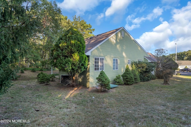 view of side of property with central AC unit, a yard, and roof with shingles