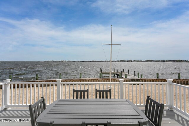 wooden deck featuring a water view, outdoor dining area, and a boat dock