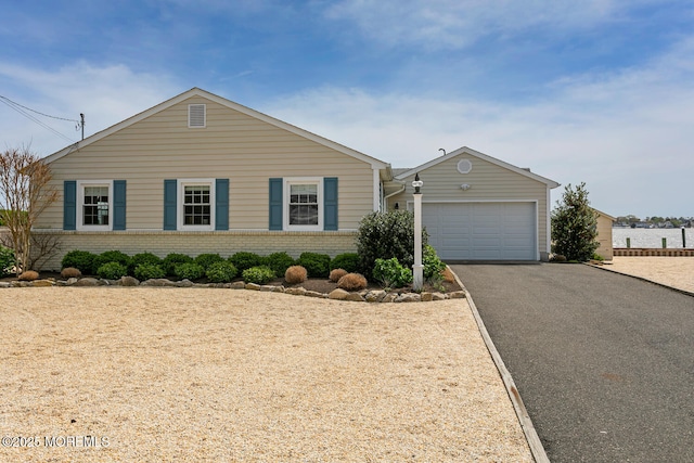 ranch-style home featuring brick siding, a garage, and aphalt driveway
