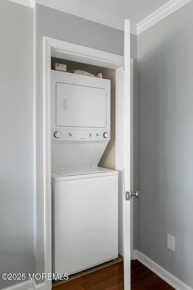 laundry area featuring crown molding, baseboards, dark wood-style floors, and stacked washer / dryer