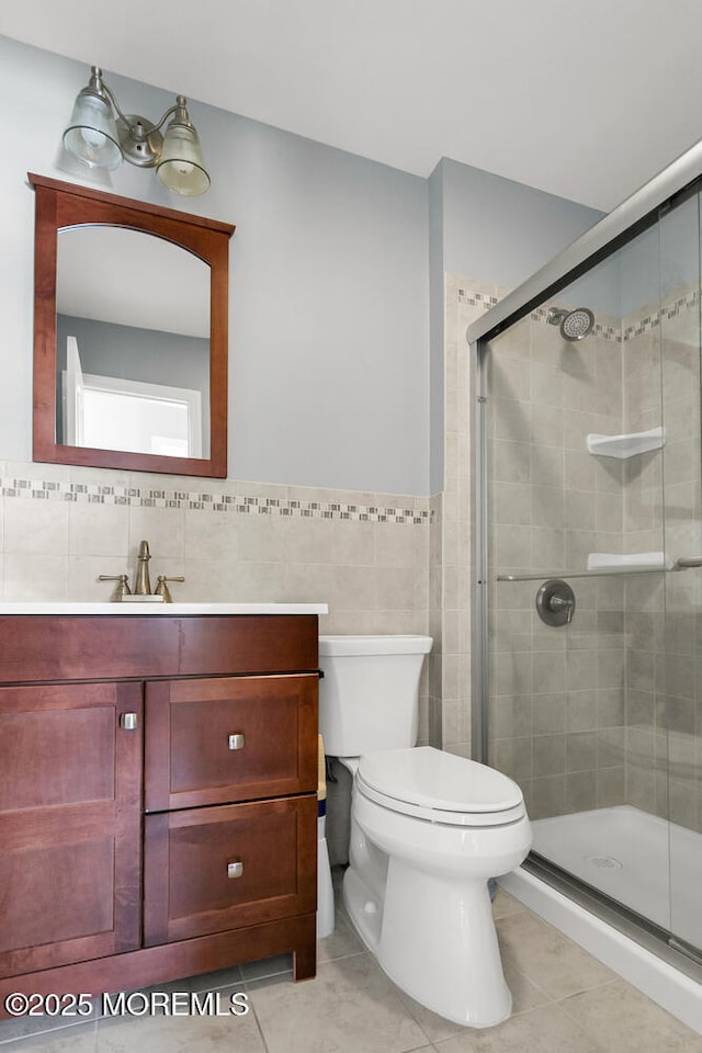bathroom featuring tile walls, a shower stall, vanity, tile patterned floors, and toilet