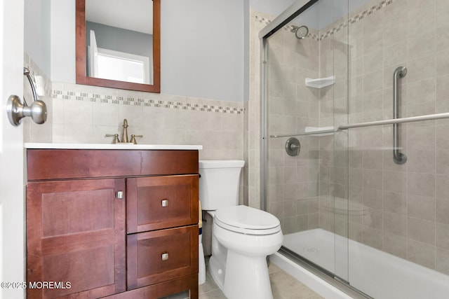 full bath featuring vanity, a shower stall, toilet, and tile walls