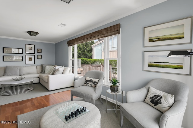 living room featuring crown molding, baseboards, visible vents, and wood finished floors