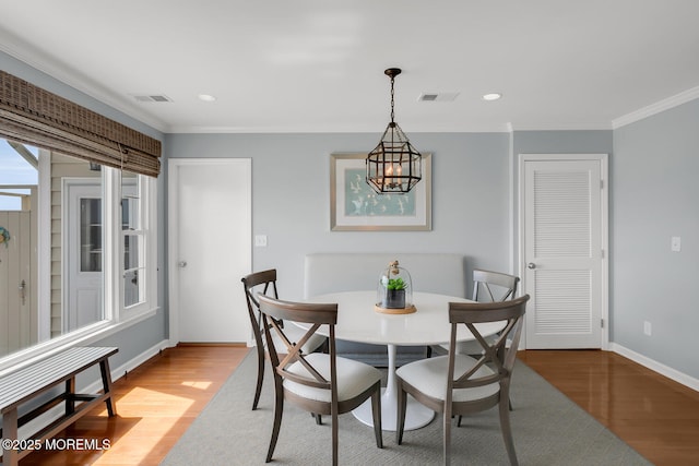 dining space with ornamental molding, wood finished floors, and visible vents
