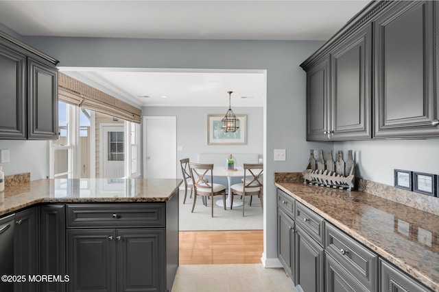 kitchen with stone countertops, a peninsula, light tile patterned floors, and an inviting chandelier