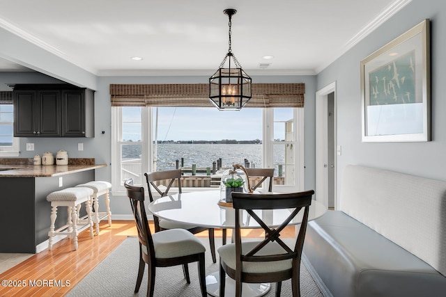 dining room with crown molding, plenty of natural light, light wood-style flooring, and a chandelier