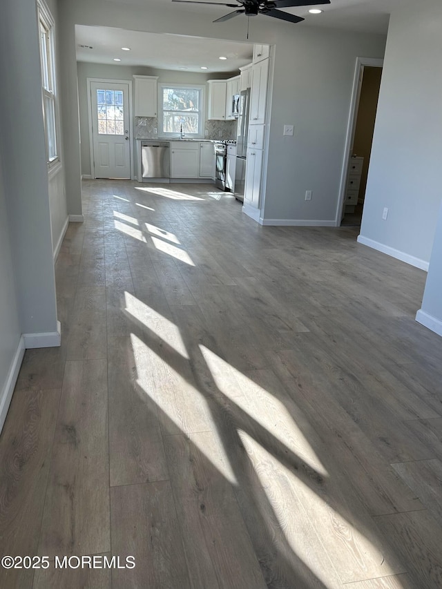 unfurnished living room featuring ceiling fan, hardwood / wood-style floors, recessed lighting, and baseboards