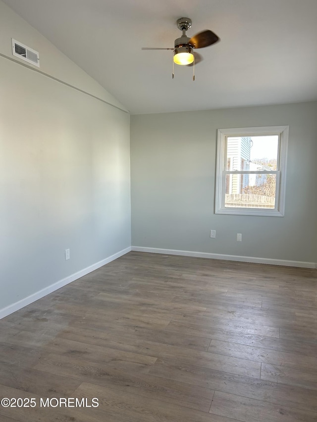 unfurnished room with wood finished floors, ceiling fan, baseboards, visible vents, and lofted ceiling