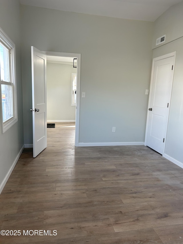 unfurnished room featuring visible vents, wood finished floors, and baseboards
