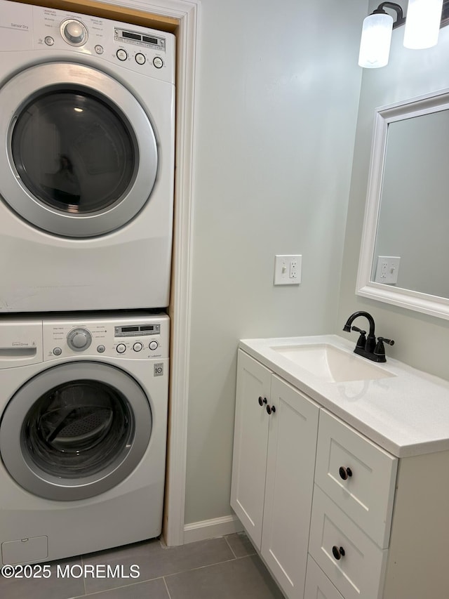 laundry room with tile patterned flooring, laundry area, a sink, baseboards, and stacked washing maching and dryer
