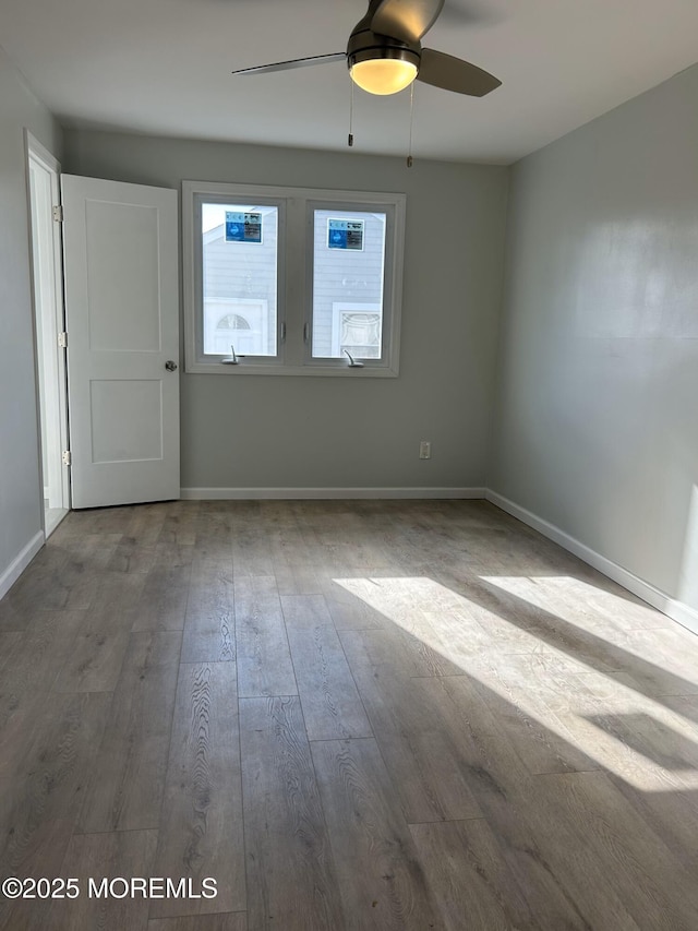 empty room featuring wood finished floors, ceiling fan, and baseboards