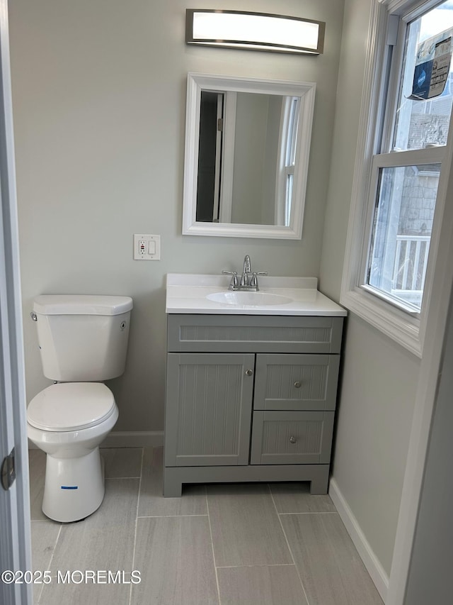 bathroom featuring toilet, tile patterned flooring, vanity, and baseboards