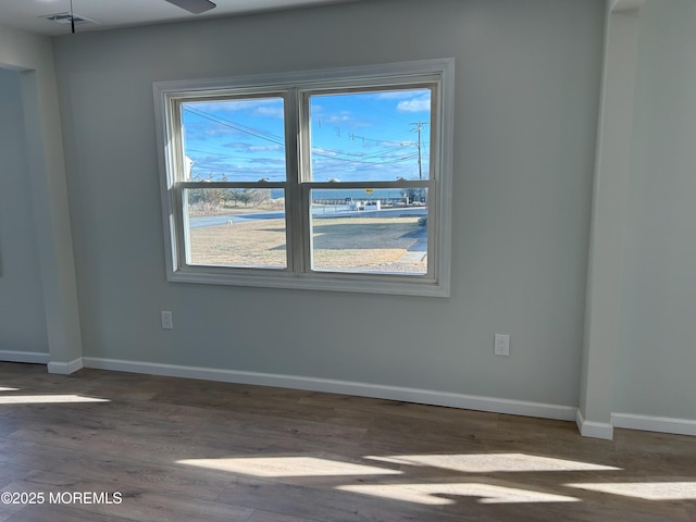 spare room featuring baseboards, visible vents, and wood finished floors