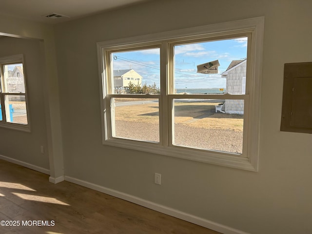interior space with wood finished floors, visible vents, electric panel, and baseboards