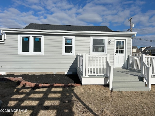 rear view of house with a deck and a shingled roof