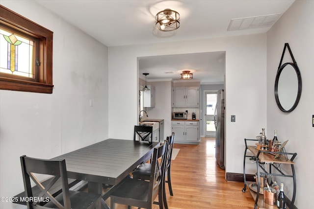 dining room with visible vents, light wood finished floors, and baseboards