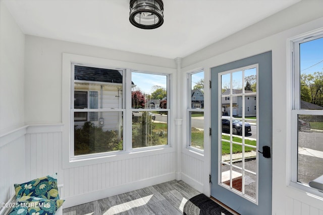unfurnished sunroom featuring wainscoting and wood finished floors