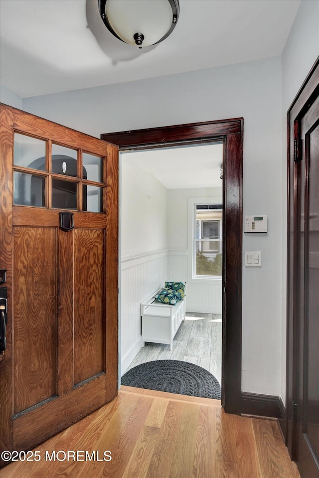 doorway to outside with baseboards, wood finished floors, and a wainscoted wall