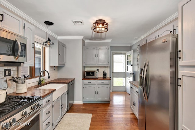 kitchen with tasteful backsplash, wood counters, appliances with stainless steel finishes, dark wood-style flooring, and visible vents