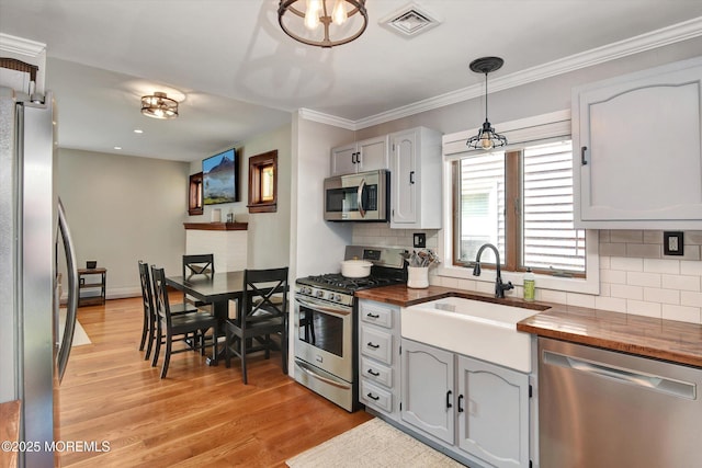 kitchen featuring light wood-style floors, butcher block countertops, appliances with stainless steel finishes, and visible vents
