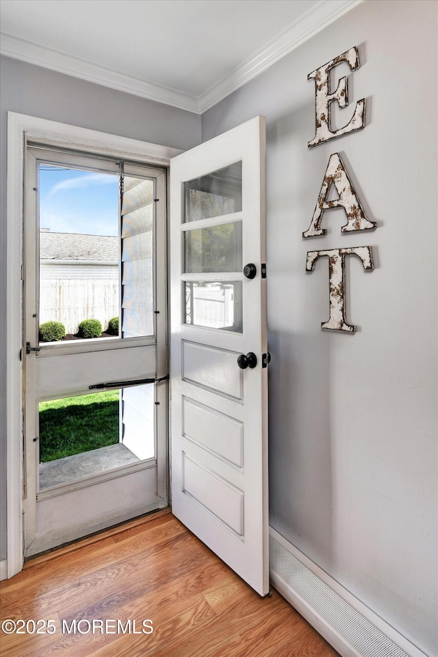 entryway with crown molding and light wood-style flooring
