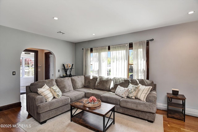 living room featuring wood finished floors, recessed lighting, visible vents, and arched walkways