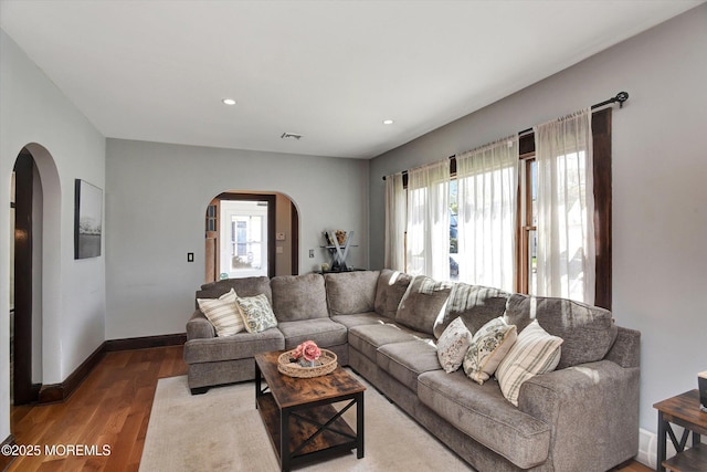 living room with recessed lighting, arched walkways, wood finished floors, and baseboards
