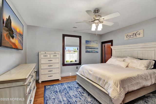 bedroom featuring baseboards, visible vents, wood finished floors, and a ceiling fan