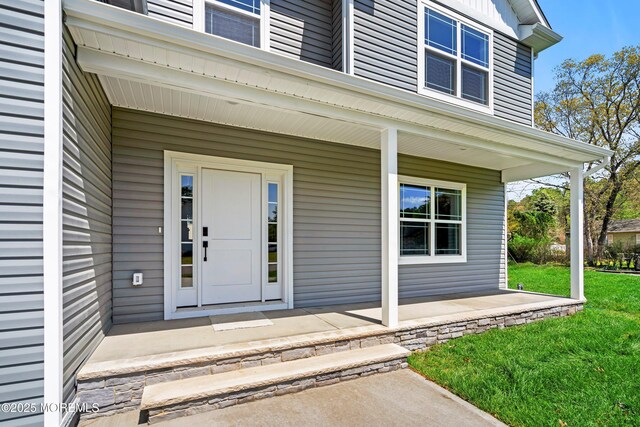 entrance to property with a porch and a lawn