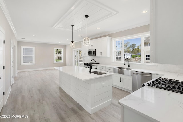 kitchen with light stone counters, a sink, light wood finished floors, and stainless steel appliances