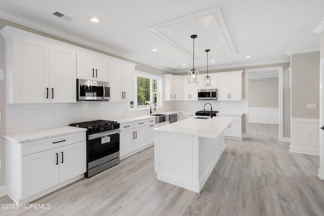kitchen featuring crown molding, stainless steel appliances, visible vents, and a sink