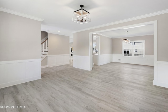 unfurnished living room with light wood-style floors, wainscoting, stairway, an inviting chandelier, and ornamental molding