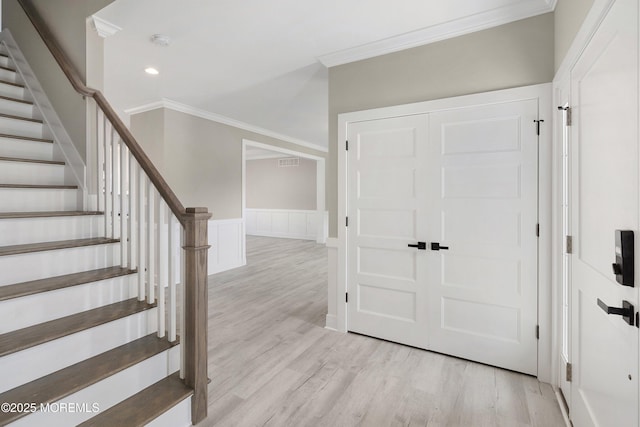 entryway featuring light wood-type flooring, ornamental molding, stairs, and recessed lighting