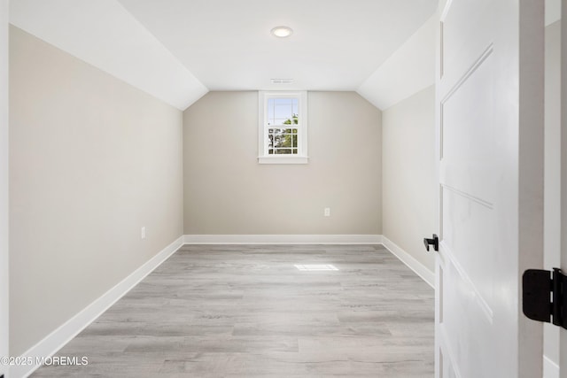 additional living space featuring baseboards, light wood finished floors, and vaulted ceiling