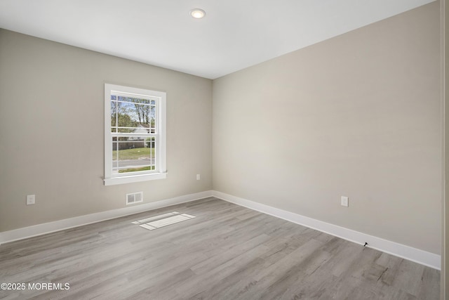 unfurnished room featuring baseboards, light wood-style flooring, and visible vents