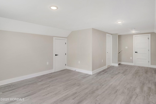 spare room with recessed lighting, baseboards, light wood-style flooring, and lofted ceiling