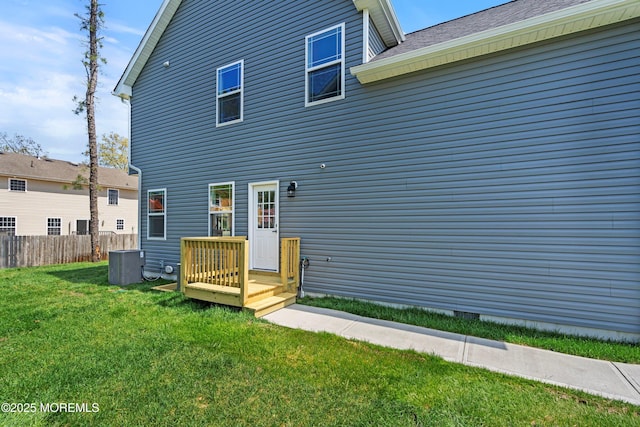 rear view of property with a lawn, central AC unit, and fence
