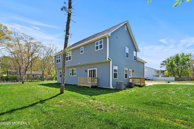 rear view of property featuring central AC unit, a yard, and a deck