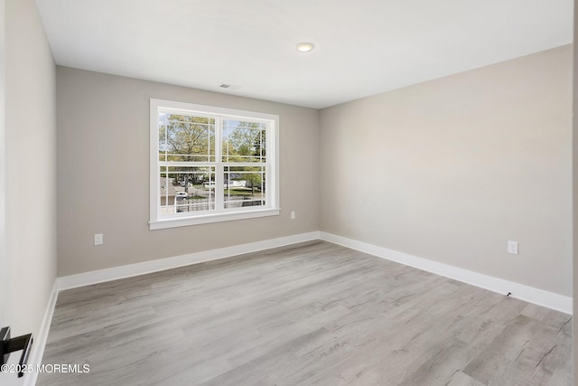 empty room featuring baseboards, light wood-style flooring, and visible vents