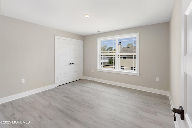 unfurnished bedroom featuring baseboards, a closet, and light wood-type flooring